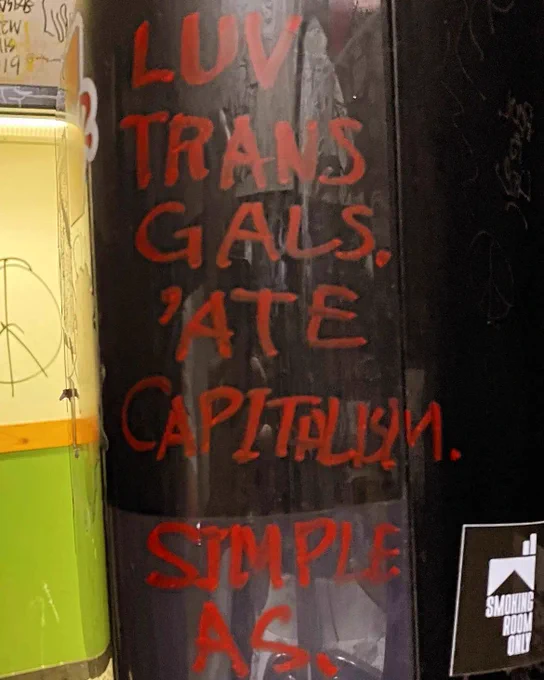 "Love trans girls, hate capitalism" written on a wall with red marker