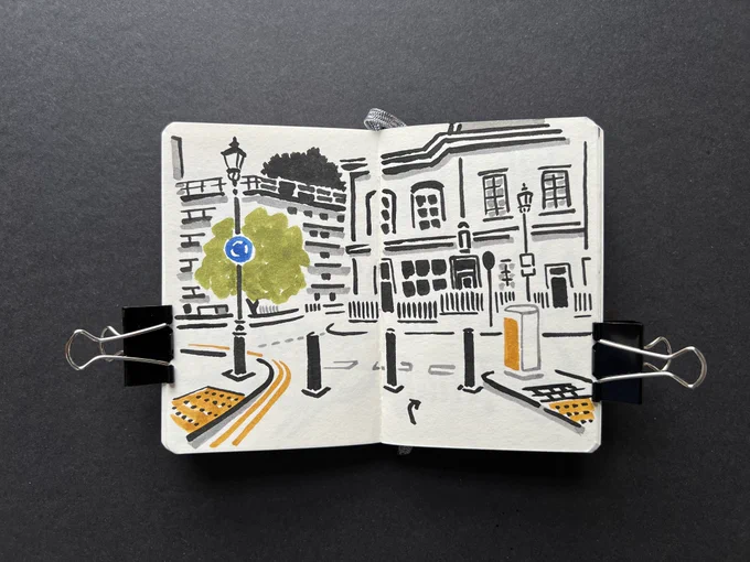 Sketchbook spread with brush pen ink illustration — cycle lane view towars houses and buildings on a quiet street in central London.