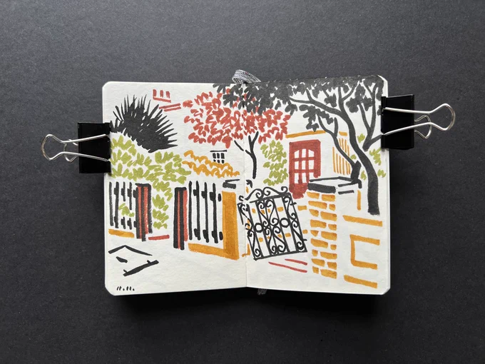 Sketchbook spread with brush pen ink illustration — trees with small gate and door of a house in urban area