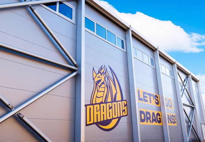Exterior of new sports hall at Harrow with Dragons logo and "Let's Go Dragons" design