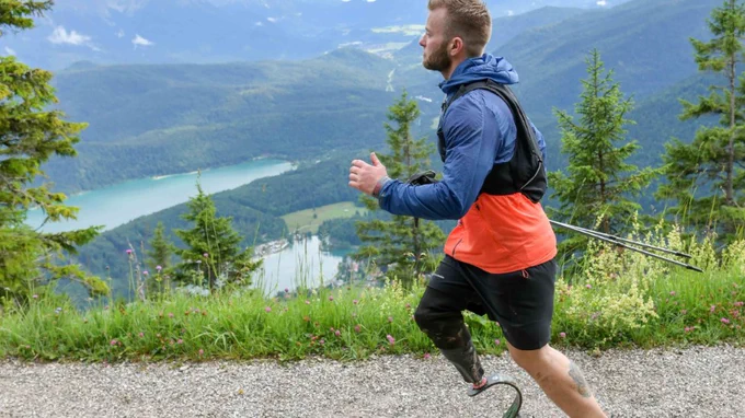 Jamie Gane runs along road with view over trees - alumni and adaptive athlete
