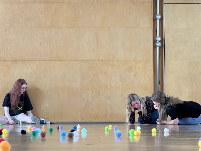 Three young women sitting on the floor during a workshop