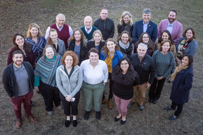Group of people standing together looking up at the camera and smiling