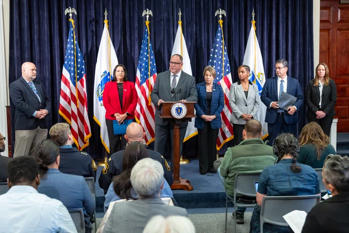 Colonel Mawn at podium with Governor Healey, LG Driscoll, AG Campbell and others behind him. 