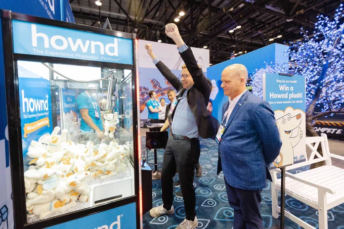 Two IAAPA Leaders celebrate at the Hownd crane game as they successfully retrieve one of the Hownd plushes from the machine!