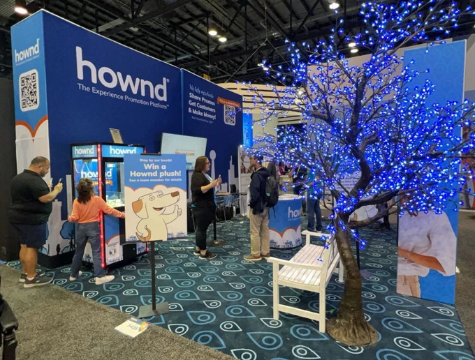 A side picture of the Hownd booth featuring our signage and signature blue trees!