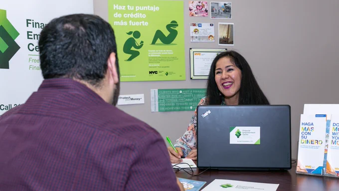 NYC Financial Empowerment Center counselor behind her laptop and writing down notes as she listens to client during their financial counseling session. 
