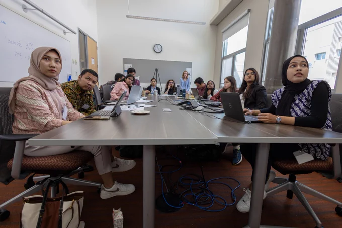A group of people sit at a table in a conference room. 