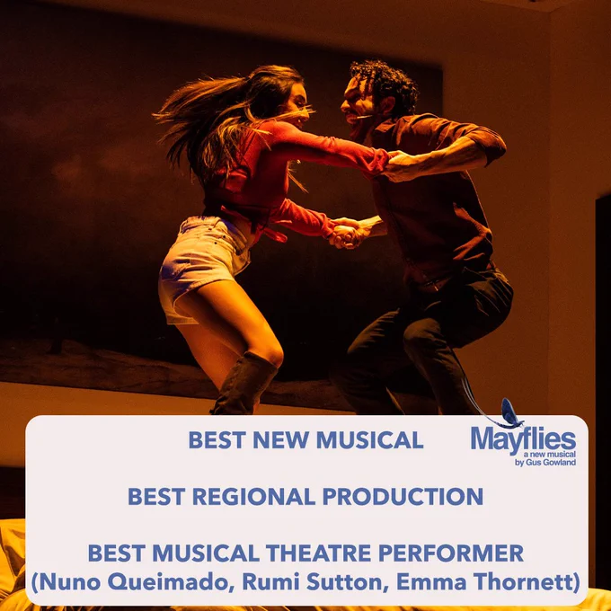 A man and a woman holding hands jumping on a bed. There is a white textbox with blue text reading "best new musical, best regional production and best musical theatre performer (Nuno Queimado, Rumi Sutton, Emma Thornett). There is a mayfly along with the words "Mayflies, a new musical by Gus Gowland" in the top right of the text box.