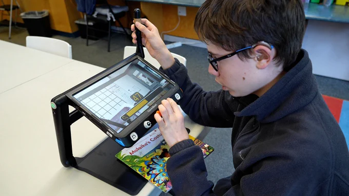 Tom using a video magnifier in a classroom.