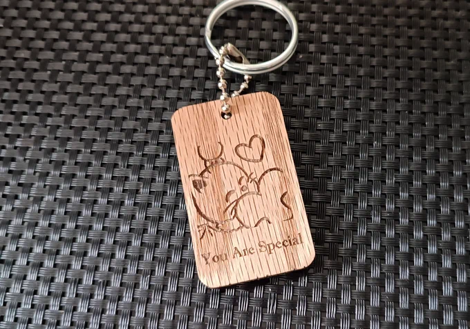 Wooden keychain with the picture of a Final Fantasy moogle hugging a heart engraved, with the inscription "you are special" underneath 