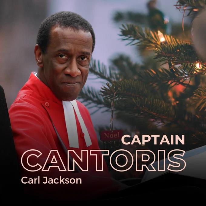 Carl Jackson sitting in front of a christmas tree.
