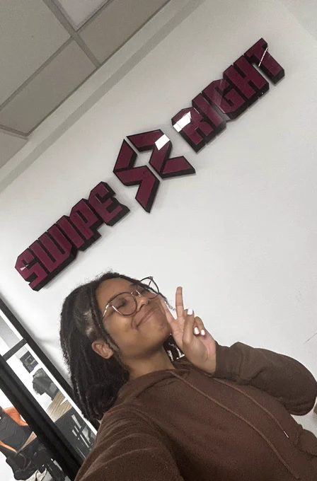 Tori smiling in front of a banner that reads ‘Swipe Right’
