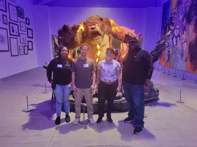 GADA scholars and members stand in front of a large video game character (Tibbers, a bear from League of Legends) display. 
