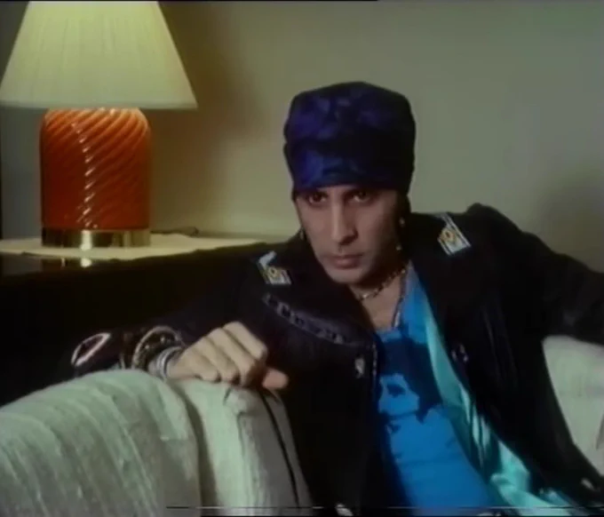 Stevie Van Zandt interviewed by David Hepworth for the BBC. Leather jacket and blue shirt underneath. Orange lampshade behind him.