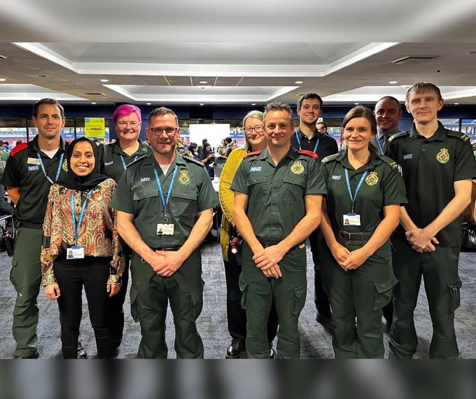 A group of student paramedics stood in uniform with members of our senior team smiling to the camera.