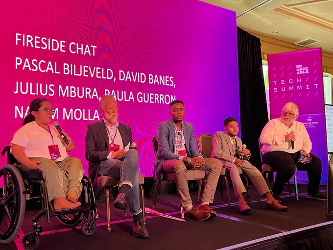 A picture that shows Paula Guerron, Pascal Biljeveld, Julius Mbura, Nayem Molla, and David Banes seated near each other on a remarkable stage. They are all holding microphones.