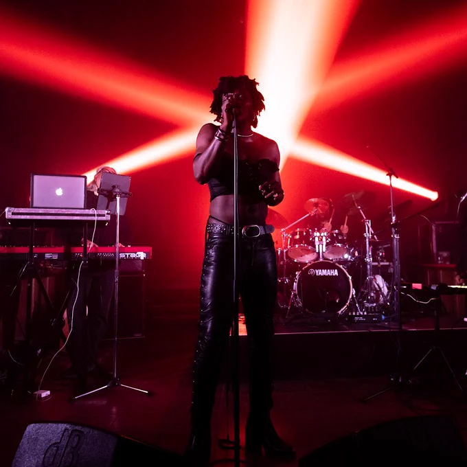 Desire Marea performs on stage, illuminated by red strobe lights