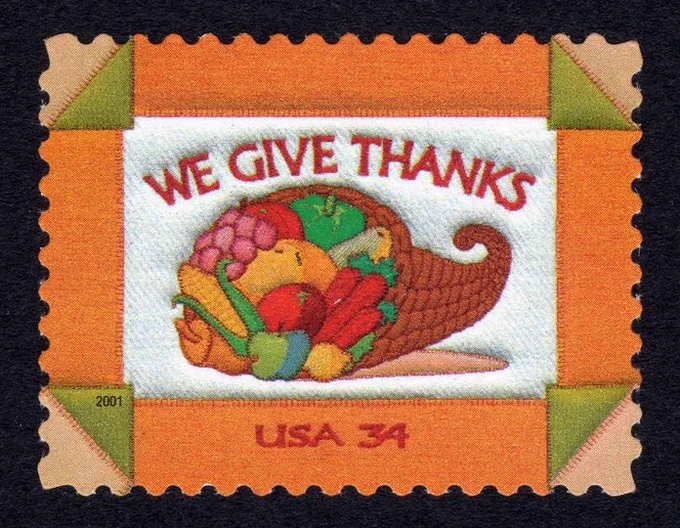 U.S. postage stamp with quilted cornucopia full of fruits and vegetables on a white and orange background