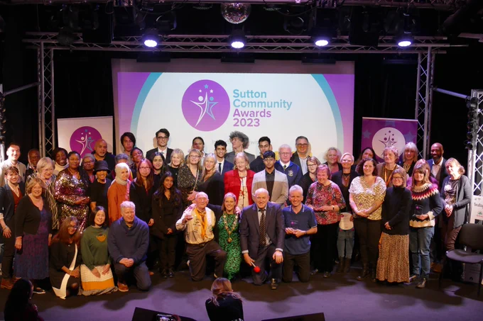 The Leader of Sutton Council, Councillor Ruth Dombey and Tim Vine standing on the stage with all of the nominees and winners at Sutton Community Awards which took place in the Cryer Arts Centre in Carshalton.