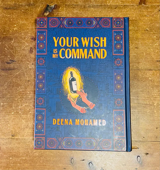 A copy of Your Wish Is My Command, written and translated by Deena Mohamed, on a wooden table. 