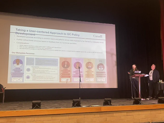 An image of two presenters standing next to a large slide presentation about taking a user-centre approach to policy development