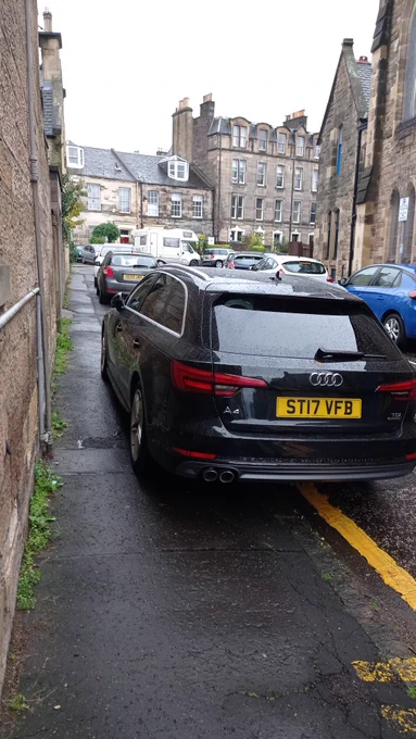 black Audi parked on a narrow pavement
