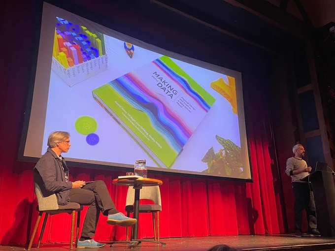A photo of me presenting Making with Data with Dietmar Offenhuber sitting at a table on the same stage.