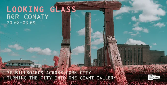 Infared image of a wooden structure infront of two cement buidlings and a large tower. A bright cloudy sky hangs in the background. Text atop the image reads: LOOKING GLASS ROR CONATY 20.08-03.09
30 BILLBOARDS ACROSS CORK CITY TURNING THE CITY INTO ONE GIANT GALLERY
