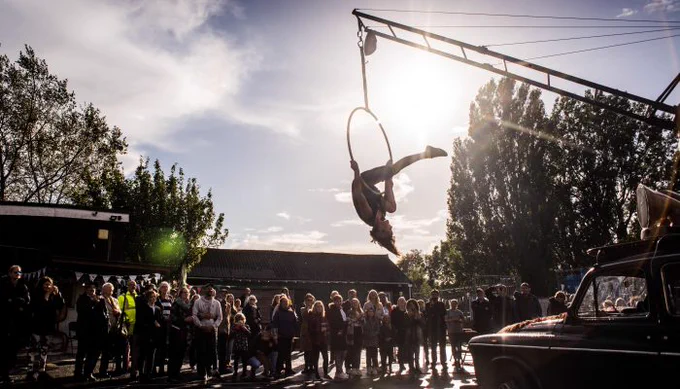 A crowd of people watching a Pirate Taxi crew member acrobatically performing during one of their circus shows