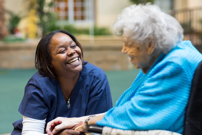 A healthcare worker laughs with a what appears to be her patient. 
