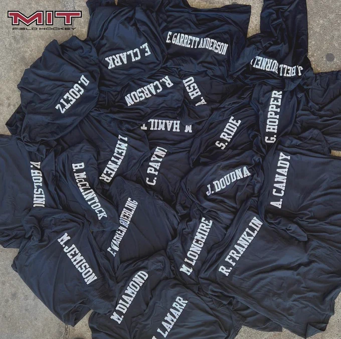 Photo of about 20 long sleeve black shirts with white names printed on the back. Names include M. Jemison, R. Franklin, C. Payne, S. Ride, E. Clark, B. McClintock, M. Hamilton, G. Hopper, A. Hsu, J. Doudna, and more.