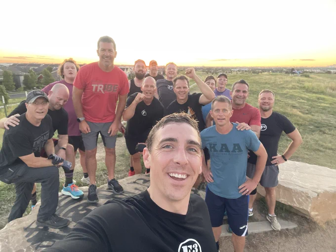 15 men in a group smiling at the camera.