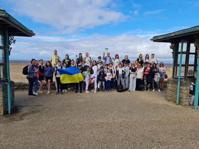 Ukrainian families gathered in a group photo holding the Ukrainian flag on the beach at Weston-Super-Mare.