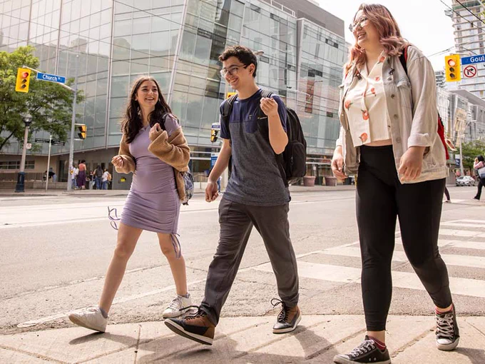 Three students with backpacks cross the intersection at Church Street and Gould Street.