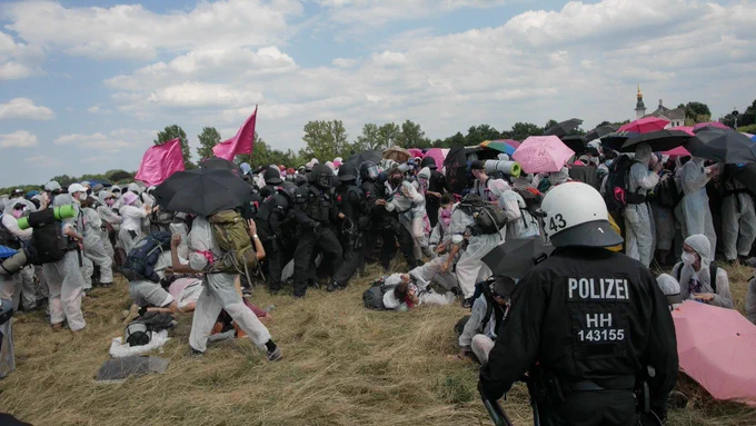 Eine prügelnde BFE einheit innerhalb des pinken Fingers, Menschen in Staubschutzanzügen fallen auf den Boden