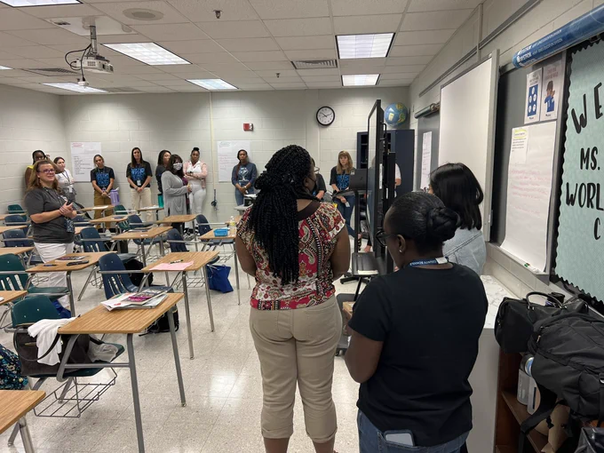 Teachers standing around a room sharing ideas.