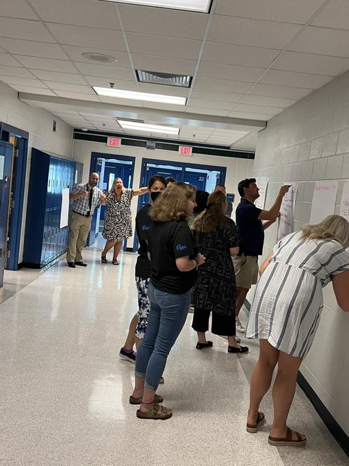 Teachers writing on poster paper in hallway.