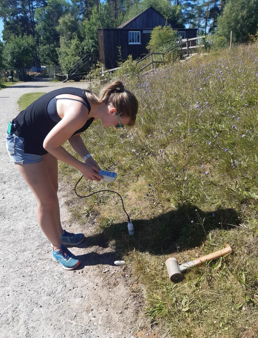 A young woman with electrical equipment by a sunny dry slope