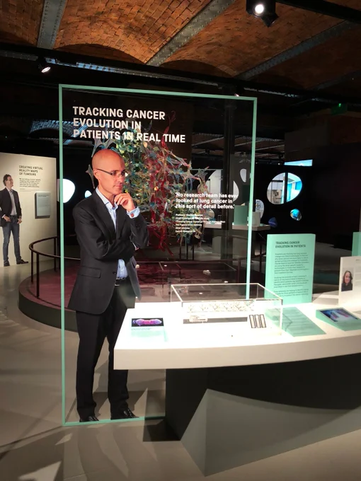 A picture of part of the exhibition. Professor Charles Swanton standing infront of a table about the the TRACERx study