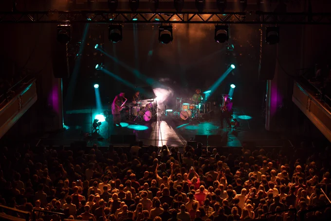 A tuba player, a saxophonist and two drummers
perform on stage in front of a full crown.