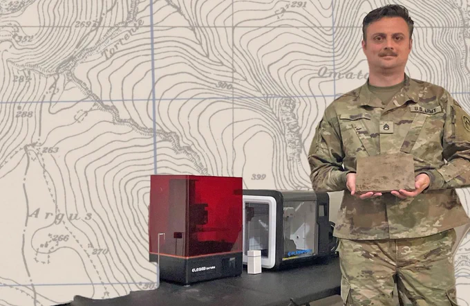 A Soldier holds a physical terrain model in his hand. He is standing next to a 3D printer. There is an image of a topographic map in the background. (Photo Credit:  U.S. Army, U.S. Army Geospatial Center, and U.S. Army Map Service map held by the Perry-Castañeda Library Maps, University of Texas Libraries, The University of Texas at Austin)