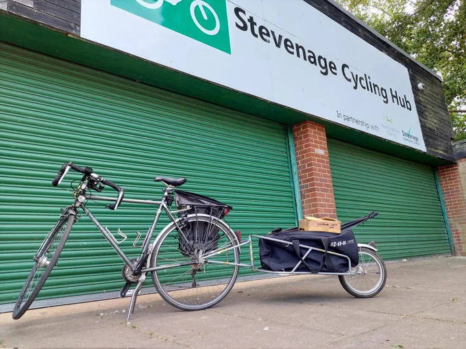 Bike and single wheel trailer in front of green roller doors and Stevenage Cycling Hub sign