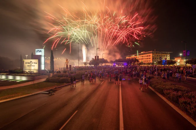 The sky is glowing with fireworks at the John Peace Boulevard entrance to UTSA Main Campus.