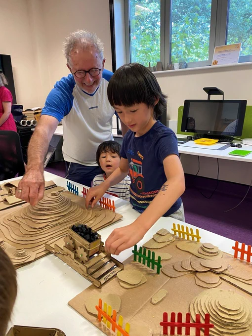 A man and two children looking at cardboard designs in one of the Innovation Labs