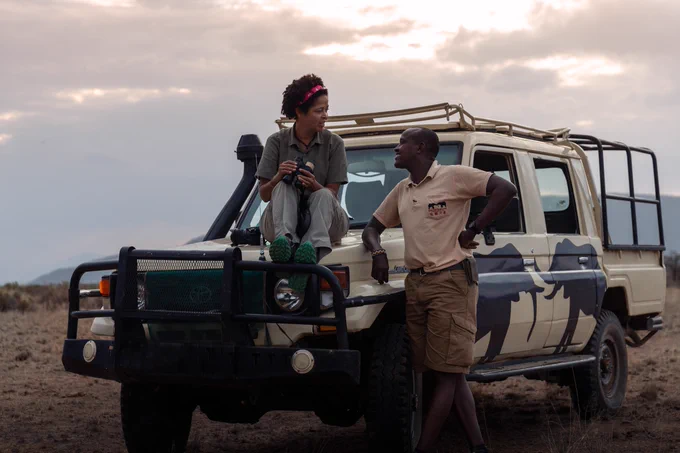 2021 Whitley Gold Award winner, Paula Kahumbu, sits on a Save the Elephants Toyota safari vehicle, talking to David from Save the Elephants charity.