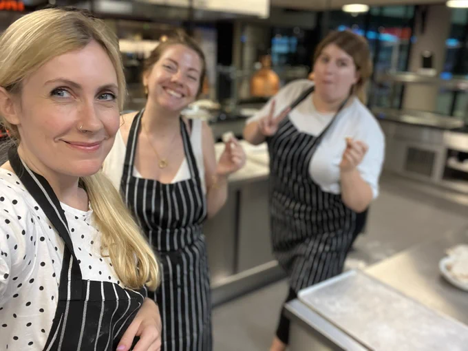 Kelly, Eleanor and Eli take a selfie in the kitchen in black and white aprons