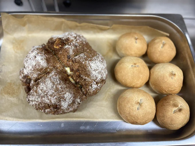 Close up of one pan of eight bread rolls and one soda bread loaf