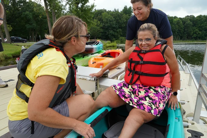 A rider settles into a kayak with assistance