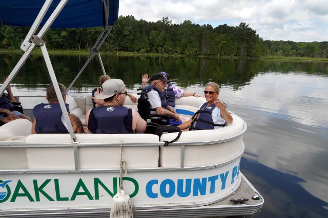 Guests wave from the back of a pontoon boat